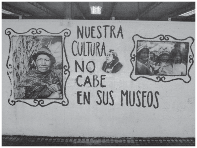 Mural em uma parede, com a frase em espanhol “Nuestra cultura no cabe en sus museos”. À esquerda, um retrato emoldurado de uma pessoa de chapéu; ao centro, um retrato menor; à direita, um retrato emoldurado de um grupo de pessoas.