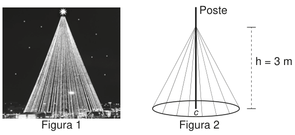 Fotografia noturna de uma iluminação em forma de cone, semelhante a uma árvore de Natal. Mangueiras luminosas retas descem do topo até pontos ao redor da base circular. Há uma estrela luminosa no topo.