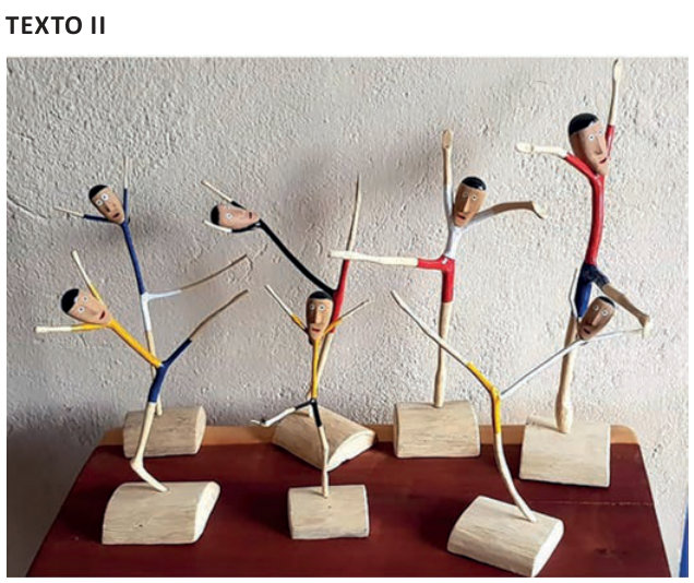 Fotografia de esculturas de bailarinos feitas com gravetos de madeira. As cabeças são entalhadas e pintadas; os galhos finos formam braços e pernas alongados, em diferentes poses de dança. Os corpos têm partes pintadas de azul, amarelo, vermelho, branco e preto. Cada escultura está fixada em uma base de madeira clara.